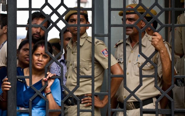 Indian court staff and policemen watch demonstrators shout slogans following the sentencing of four men convicted of rape and murder at the Saket courthouse in New Delhi on September 13, 2013. A judge sentenced four men to death September 13 for the fatal gang rape of an Indian student on a bus last December, triggering applause inside the packed courtroom. AFP PHOTO/MANAN VATSYAYANA        (Photo credit should read MANAN VATSYAYANA/AFP/Getty Images)
