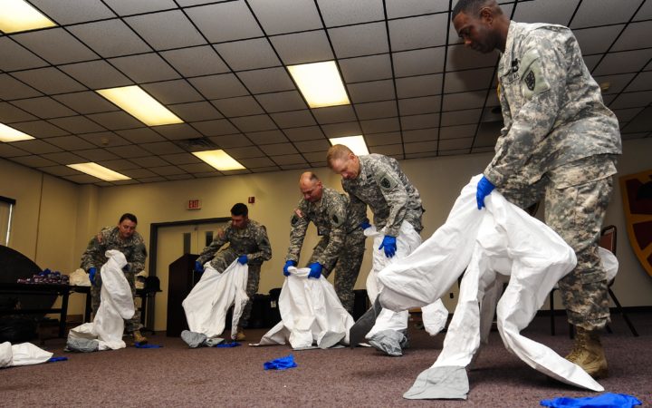 U.S. Army Soldiers from the 53rd Transportation Battalion (Movement Control), 7th Transportation Brigade (Expeditionary), learn how to don personal protective equipment at Fort Eustis, Va., Oct. 15, 2014. Although Fort Eustis personnel deploying to West Africa will not treat Ebola-infected patients, they were provided specialized training on use of PPE in the events of potential exposure. (U.S. Air Force photo by Airman 1st Class Breonna Veal) (This photo was cropped, contrasted and sharpened to emphasize the subjects.)